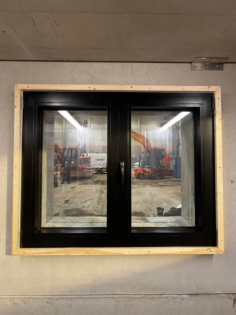 Châssis aluminium noir à deux ouvrants posé dans une ouverture encadrée de bois