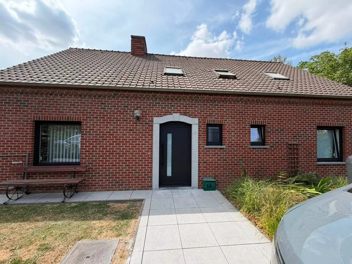 Maison en briques rouges équipée de châssis et d’une porte d’entrée noir graphite (RAL 9005) posés par Arena Invest